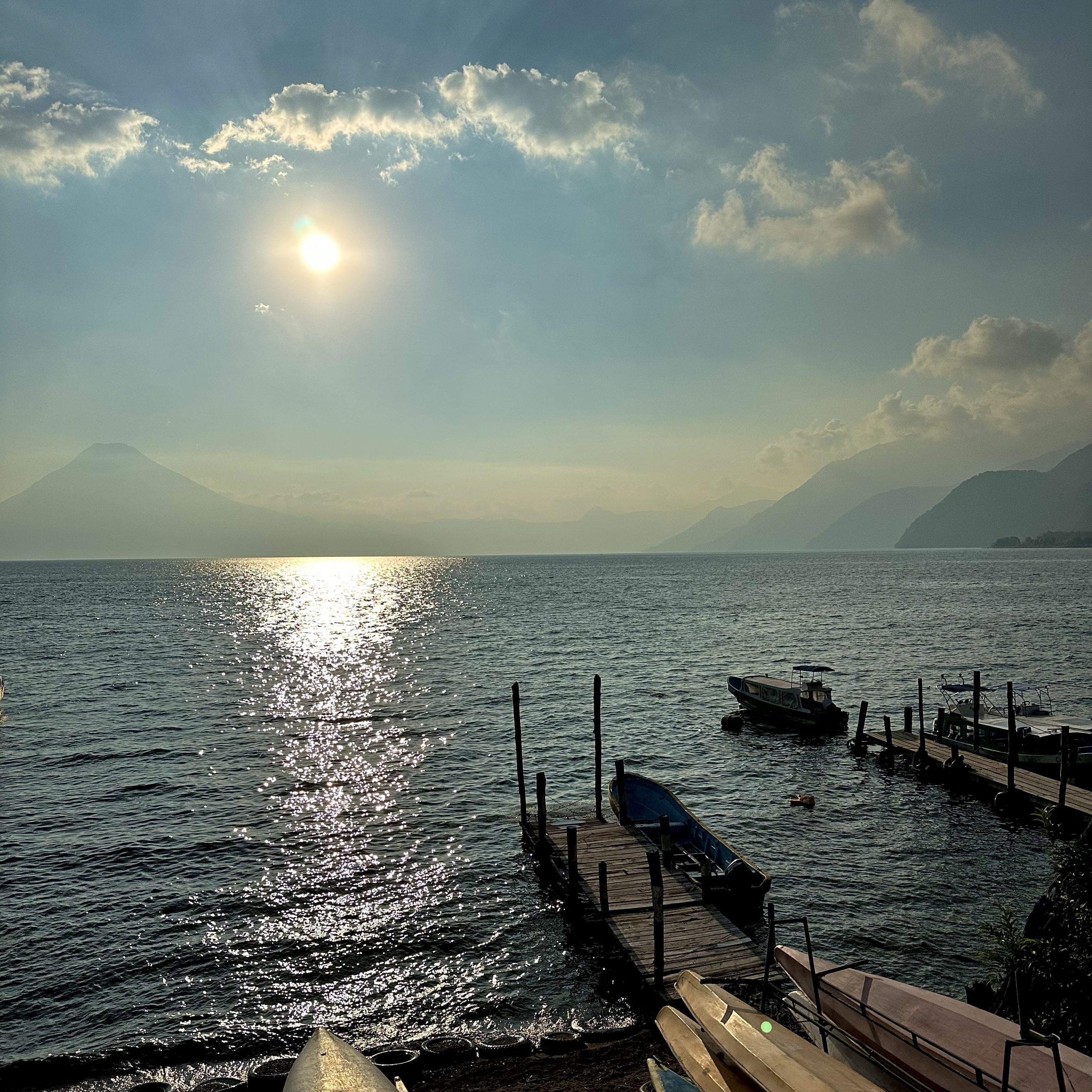 Boats on a dock by a lake with mountains in the background